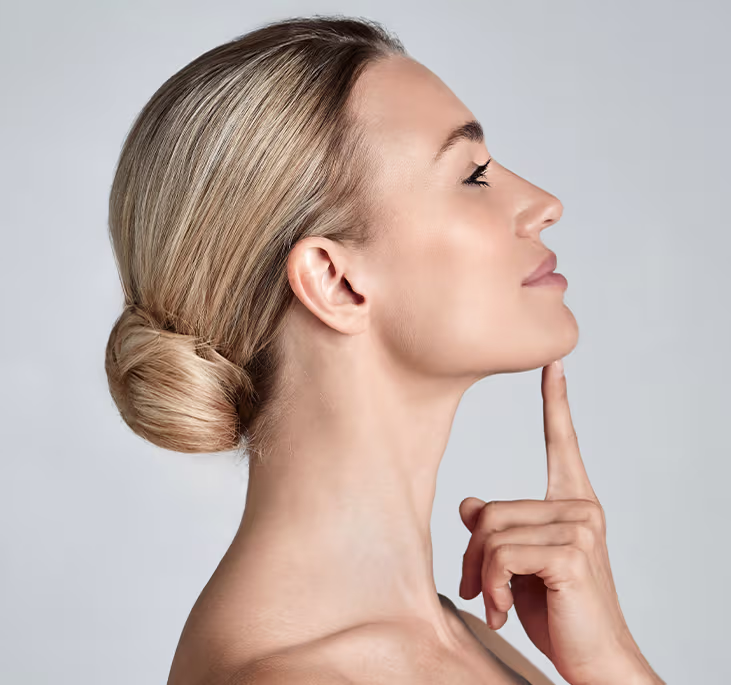 Woman touching chin in profile, representing awake chin liposuction for submental fat and jawline contouring.